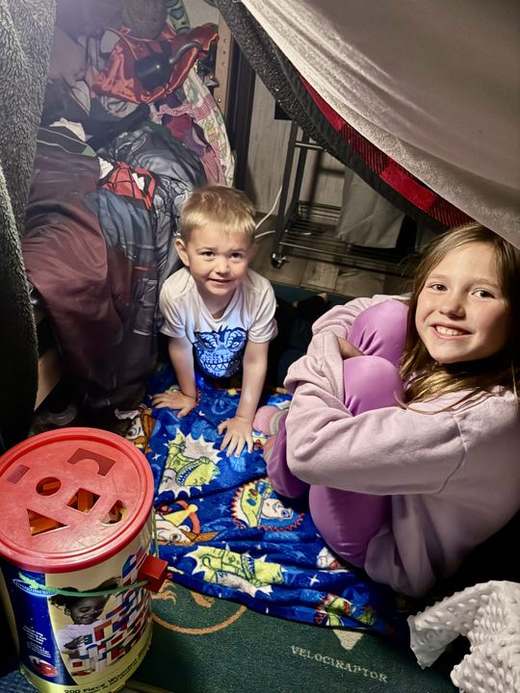 Emma and her little brother playing in a blanket fort