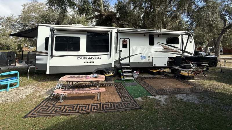 Our fifth-wheel RV set up at a campsite under big oak trees